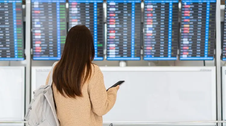 Jovem diante de painel no aeroporto