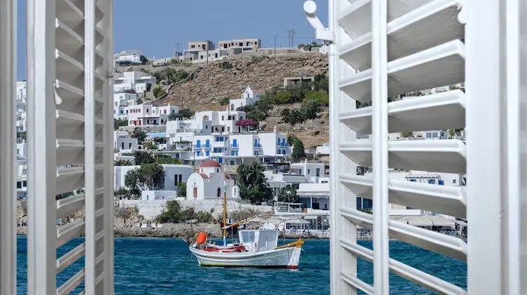 Janela aberta mostra um barco de pesca, em roteiro Grécia e Turquia