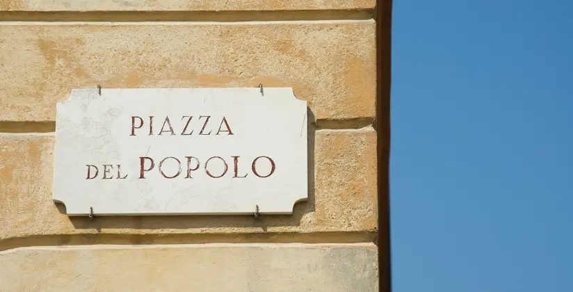 Parede com uma placa de uma praça em Roma