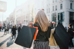 Mulher com sacolas de compras anda pela ruas