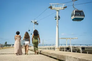 Mulheres caminham próximas ao Teleférico de Lisboa.
