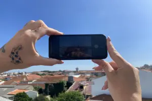 Mãos segurando telefone sobre vista a ser fotografada.