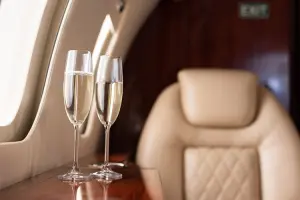 Taças de espumante e poltrona na primeira classe do avião