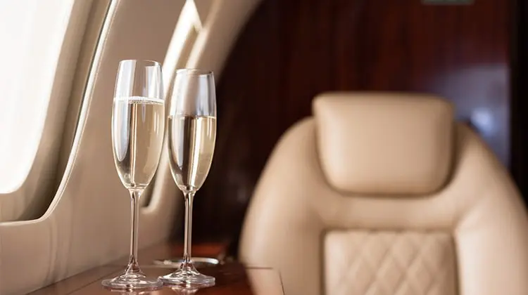 Taças de espumante e poltrona na primeira classe do avião