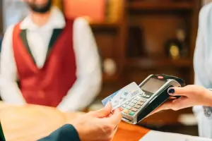 Mulher pagando com cartão via aproximação com o cartão Visa Travel Money na máquina de cartão