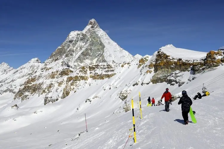 Visitantes caminhando sobre famosa montanha coberta de neve, a Matterhorn, no norte italiano.