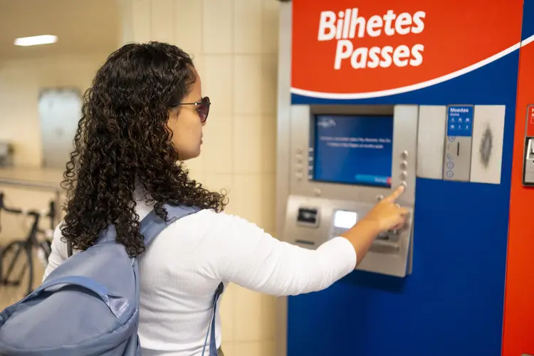 Mulher usando máquina automática para comprar passagens de trem.