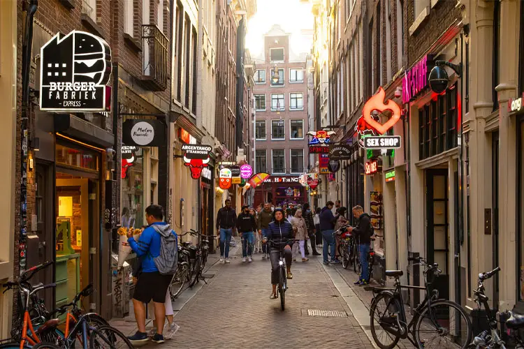 Entardecer no Centro Antigo de Amsterdam com pessoas pedalando e caminhando