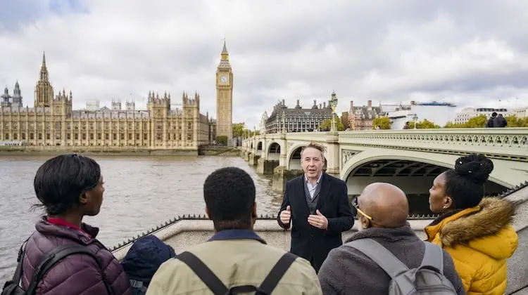 Guia turístico conversa com um grupo de viajantes em frente ao Big Ben e ao Parlamento de Londres, em um city tour em Londres
