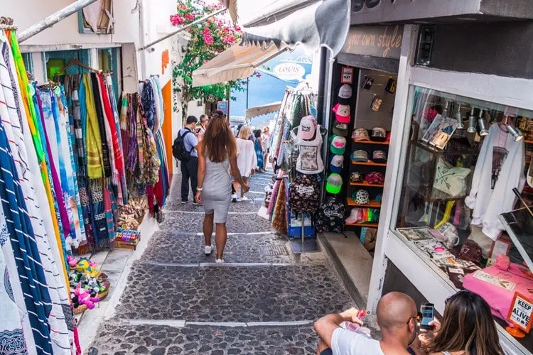 Turista andando pelas pequenas ruas comerciais de Santorini, na Grécia.