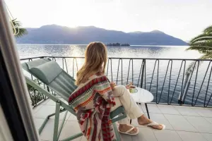 Na varanda, mulher toma café enquanto observa a paisagem