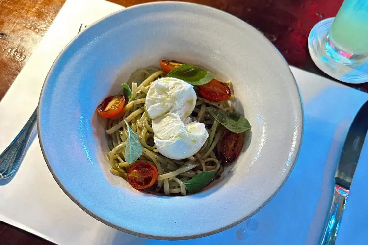 Prato de massa com burrata, tomate-cereja e manjericão servido em restaurante em Roma.