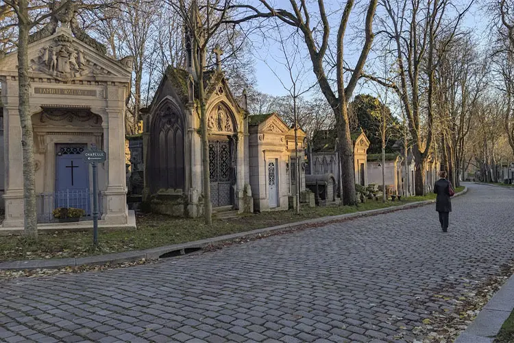 Pessoa caminhando pelo Cimetière du Père-Lachaise em fim de tarde de inverno