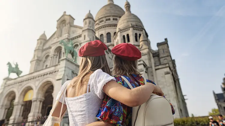 Duas turistas com seguro viagem, olhando para Basílica de Sacré Coeur, em Paris