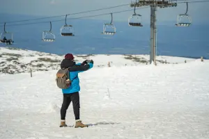 Homem de casaco azul tira foto na neve na Serra da Estrela