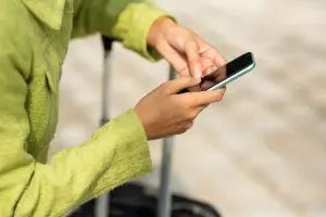 Pessoa usando celular com conexão da A Casa do Chip ao lado de uma mala de viagem