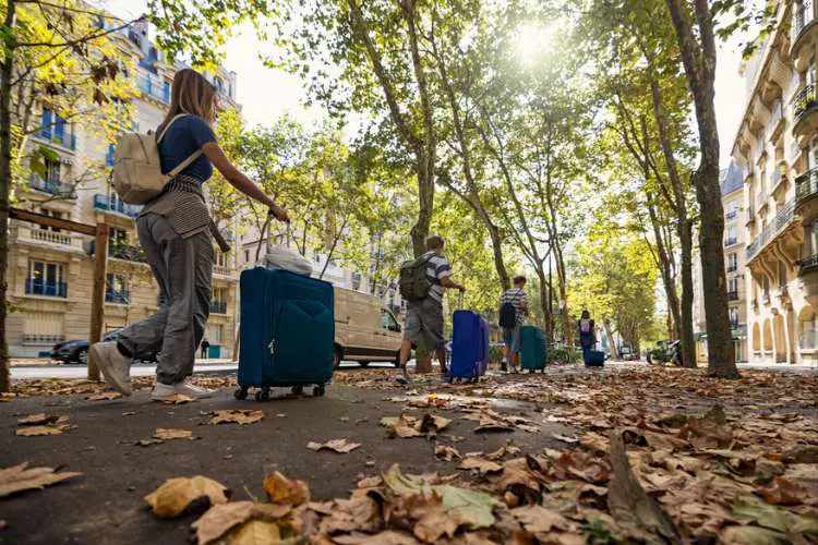 Pessoas enfileiradas caminhando com as malas