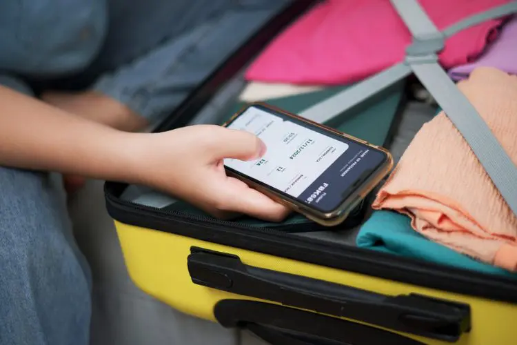 Pessoa usando a plataforma da Expedia enquanto arruma a mala