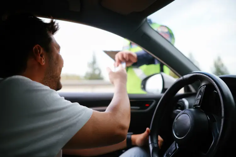 Homem entregando documento para autoridade em viagem de carro na Alemanha.