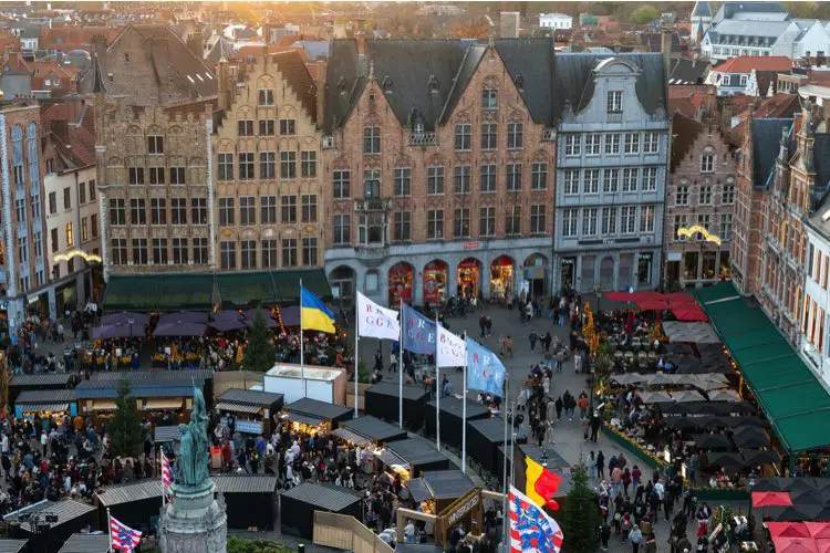 Turistas e locais caminham por mercado de Natal durante a tarde na Bélgica