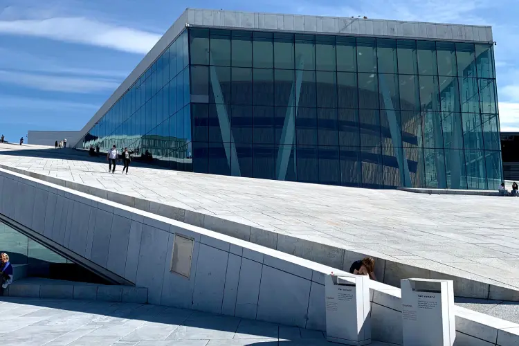 Edifício moderno da Ópera de Oslo com vidros e rampas brancas.