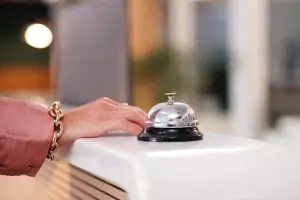 Mão de mulher ao lado de campainha de hotel