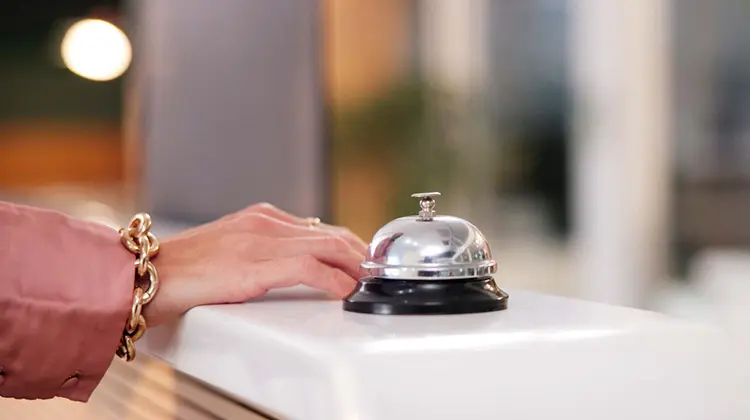 Mão de mulher ao lado de campainha de hotel