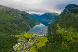 Fiorde da Noruega com montanhas verdes e um barco em passeio pelo mar
