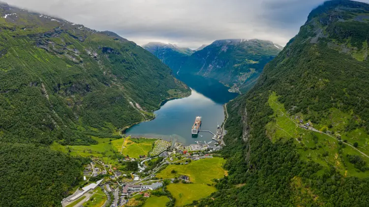 Fiorde da Noruega com montanhas verdes e um barco em passeio pelo mar