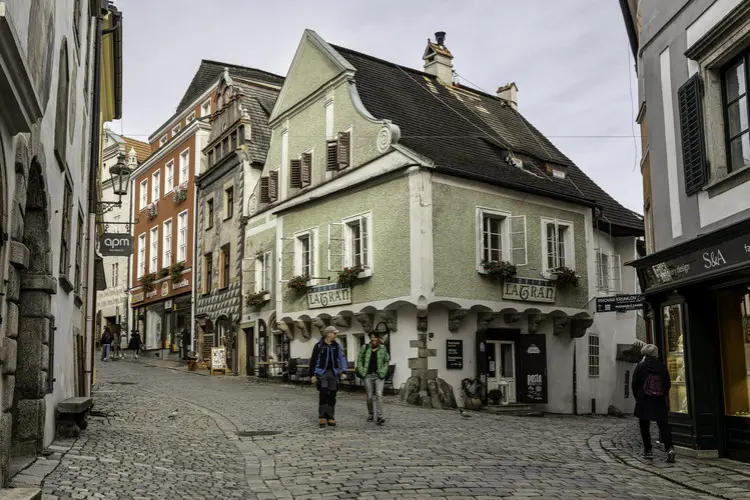 Turistas caminham em dia nublado pelas charmosas ruas medievais de Cesky Krumlov.