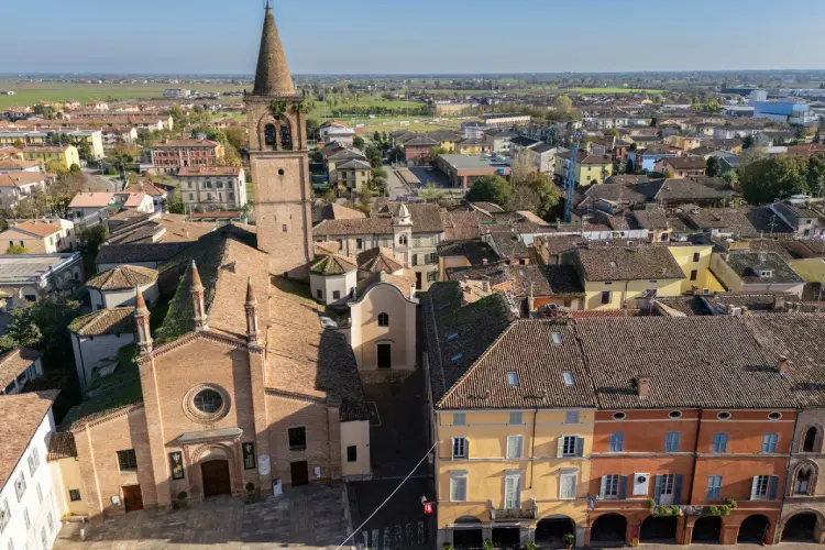 Igreja histórica de Parma cercada por casas coloridas típicas da Emilia-Romagna.