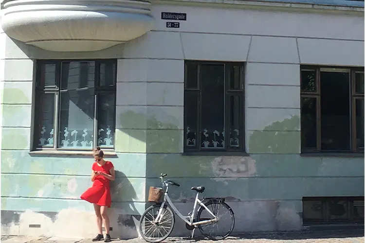 Mulher de vestido vermelho em frente a construção antiga em Copenhague