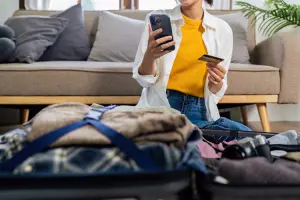 Mulher verificando aplicativo e cartão Global Account Inter, antes de viajar.