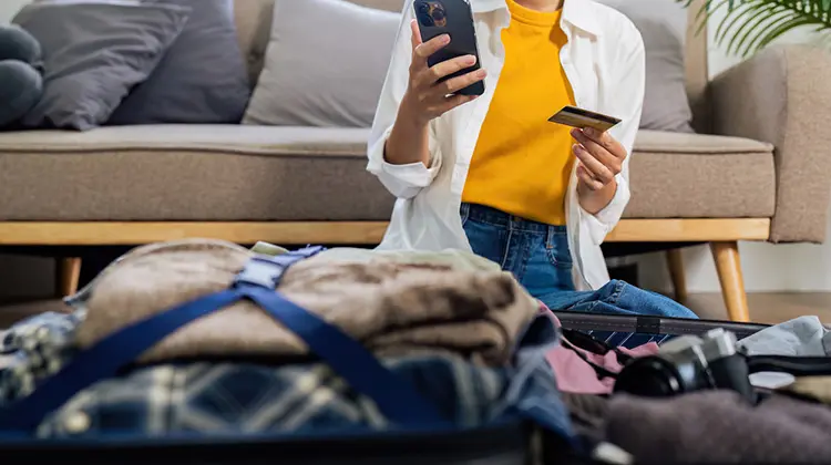 Mulher verificando aplicativo e cartão Global Account Inter, antes de viajar.
