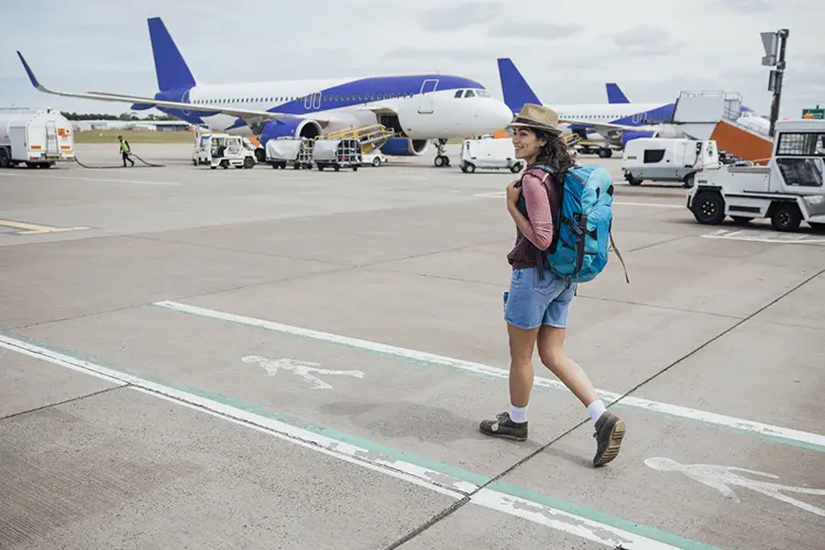 Mulher caminha para embarque em voo do seu mochilão na Europa.