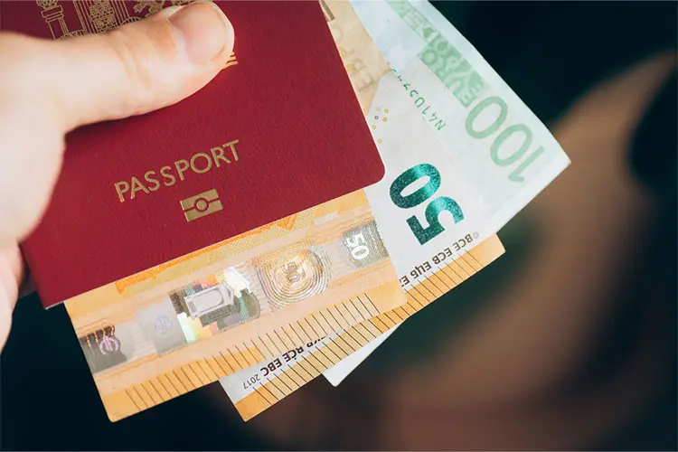 Homem segura um passaporte europeu e dinheiro em espécie