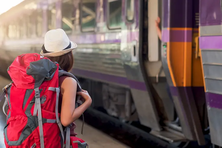 Mulher de mochila espera o trem.