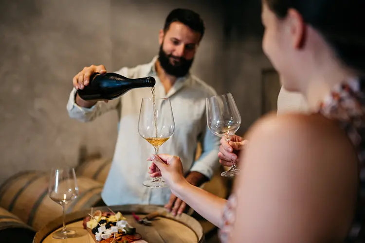 Grupo de amigos em cave fazendo degustação de vinho do Porto branco.