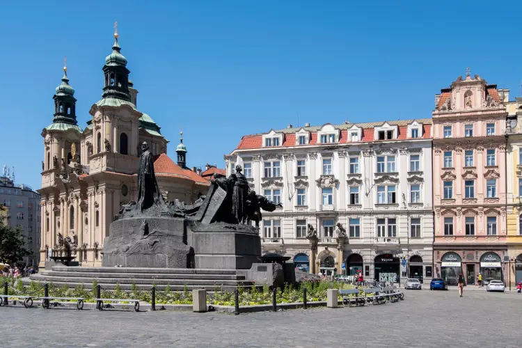 Praça histórica na Cidade Velha de Praga com monumento central e arquitetura antiga ao redor