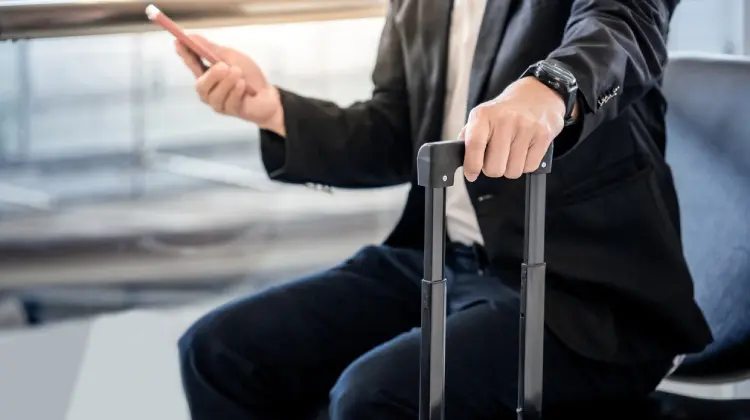 Homem com mala em aeroporto usando celular com Claro Passaporte