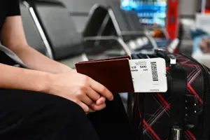 Pessoa com passaporte e bilhete em mãos antes de embarcar em voo com passagem aérea barata.