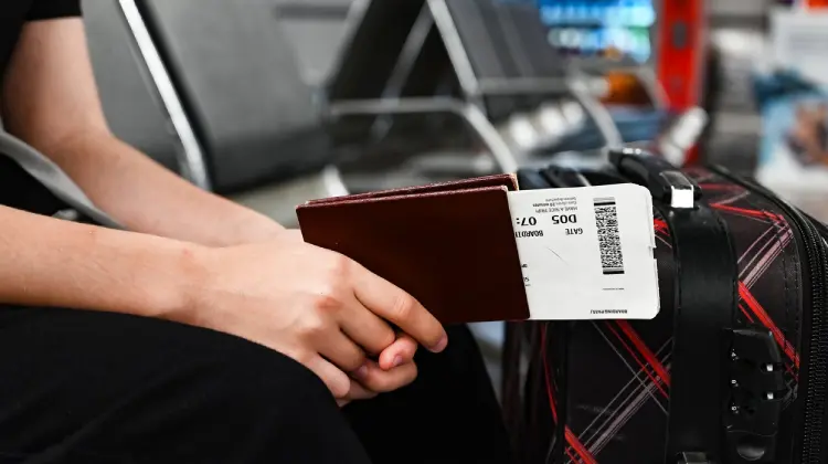 Pessoa com passaporte e bilhete em mãos antes de embarcar em voo com passagem aérea barata.