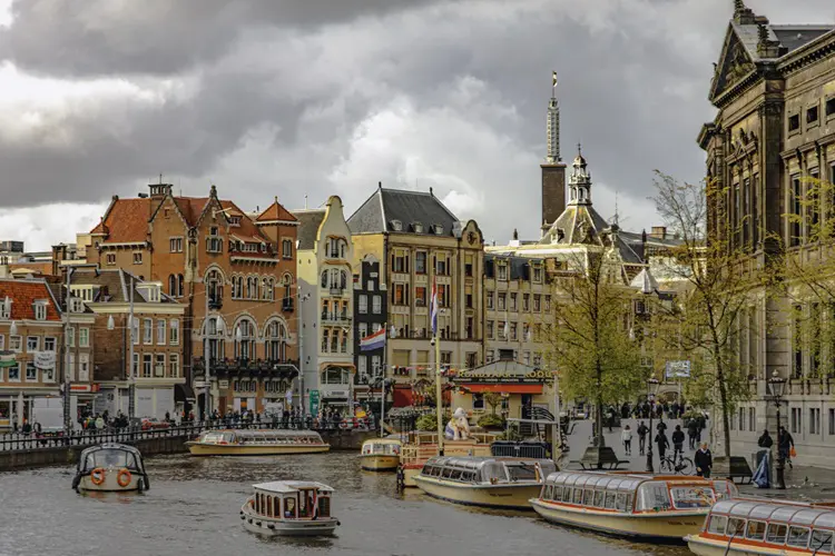 Canal de Amsterdam cheio de barcos em dia nublado de outono.