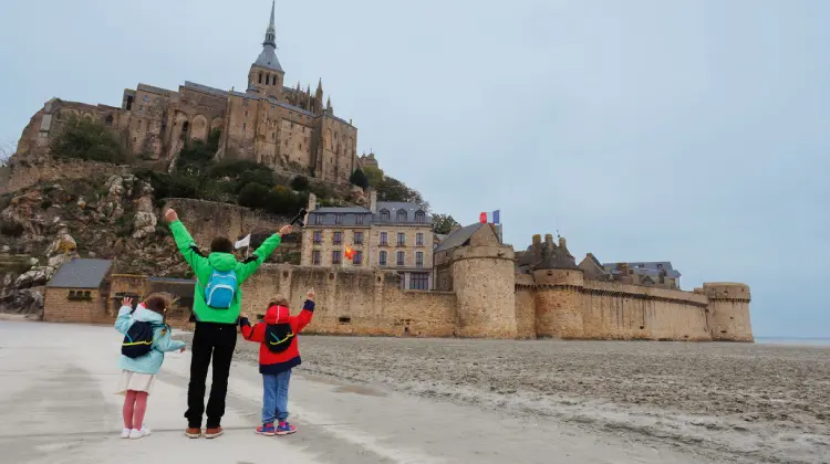 Família na frente do Monte Saint Michel em viagem pela França com crianças