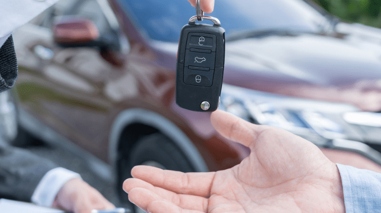 Pessoa entrega uma chave de carro alugado pela Rentcars.