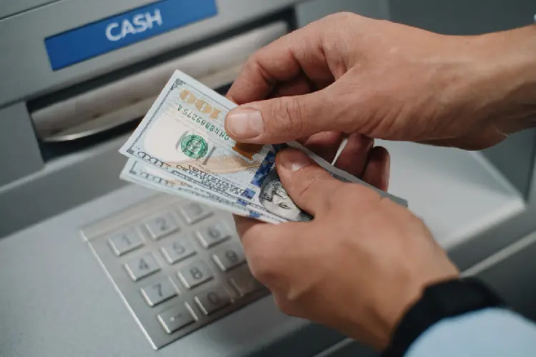 Pessoa sacando notas de dólar ao utilizar o DolarApp para viagem. 