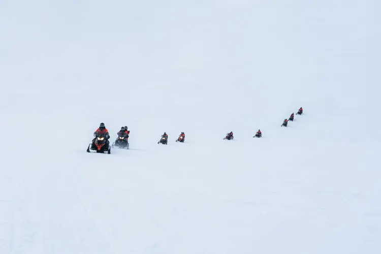 Turistas em moto de neve no inverno da Finlândia