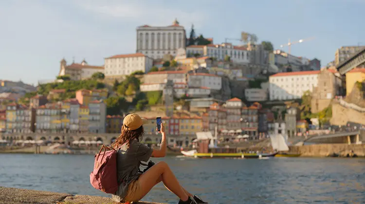 Mulher fotografando a ribeira do Porto, uma das coisas para fazer em Portugal
