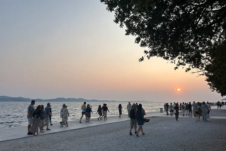 por do sol em Zadar com pessoas caminhando perto do mar