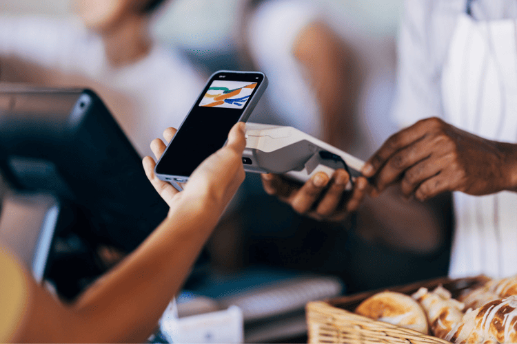 Pessoa realiza pagamento por aproximação com o celular em uma maquininha de cartão, em um estabelecimento